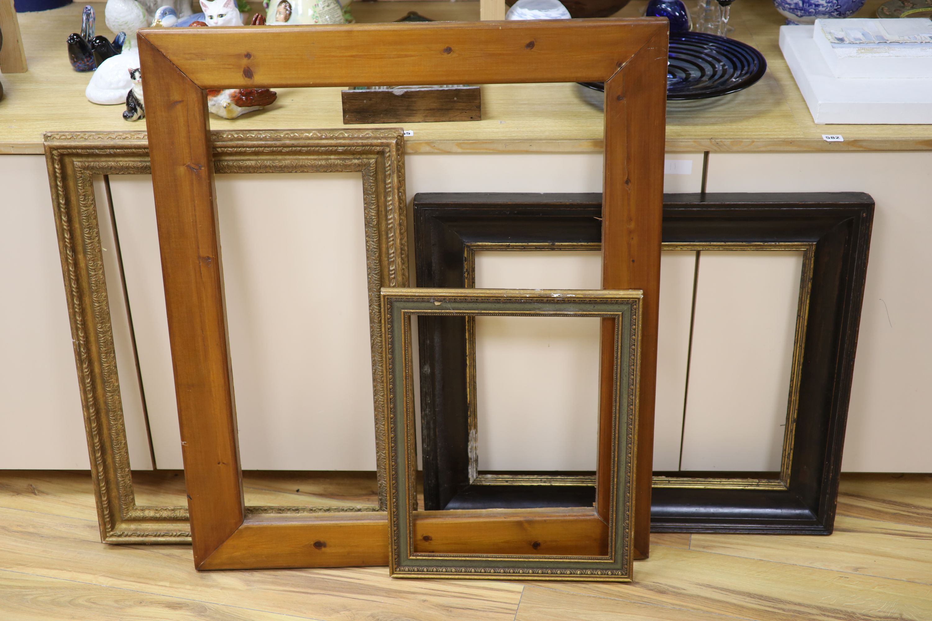 An early 19th century English parcel gilt and ebonised hardwood picture frame, aperture 56 x 47cm, a plain wood frame and two gilt frames